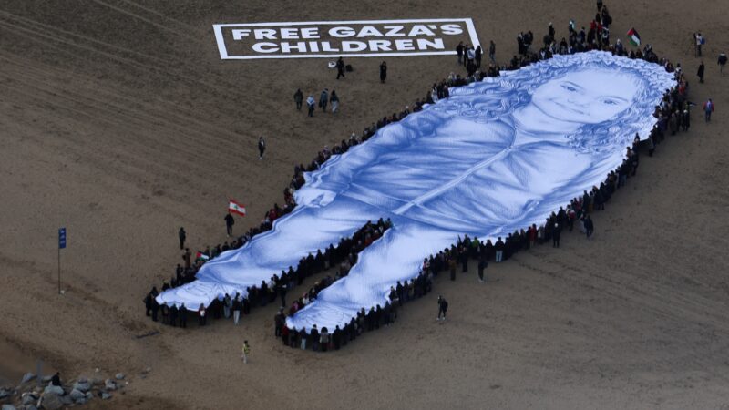 Retrato gigante de menina morta na guerra de Gaza é estendido em praia de Barcelona