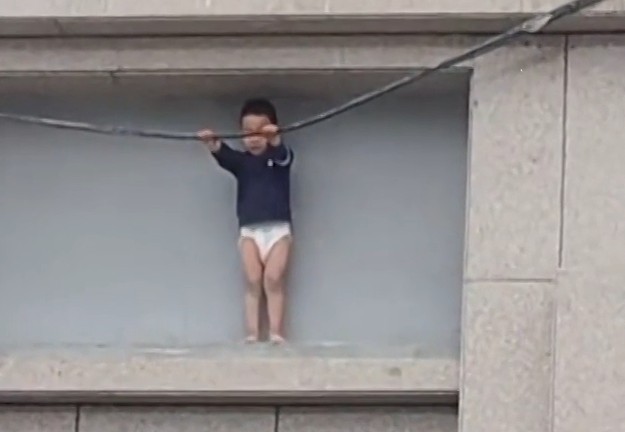 VÍDEO: Menino de 3 anos fica preso do lado de fora de prédio a 10 metros de altura na China